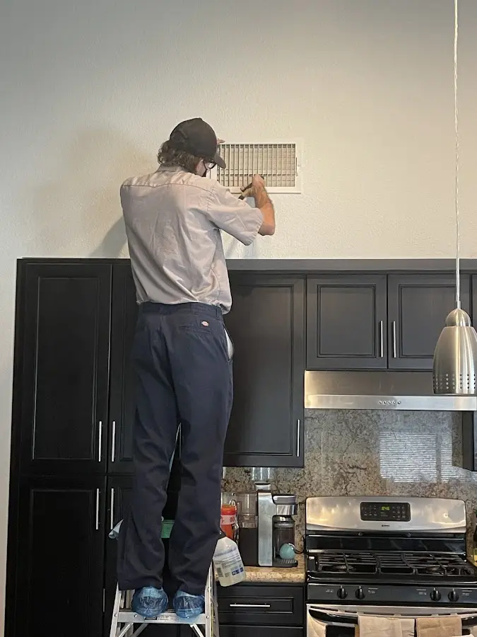 Technician inspecting an air vent during HVAC service in St. Charles
